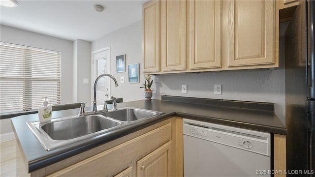 kitchen with dishwasher, sink, black refrigerator, and light brown cabinetry