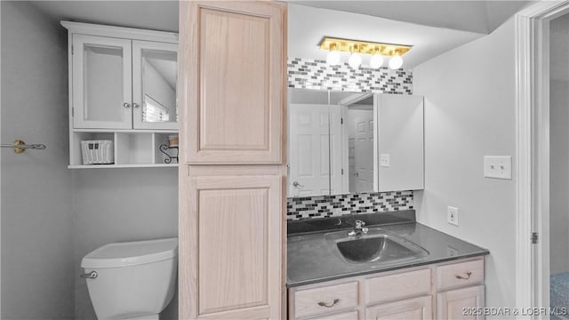 bathroom featuring vanity, toilet, and backsplash