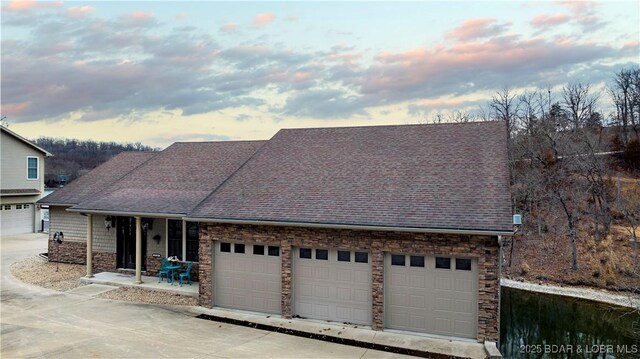 27112 White Horse Cir, Rocky Mount, MO 65072 - view of front of house with a shingled roof, a garage, stone siding, and driveway