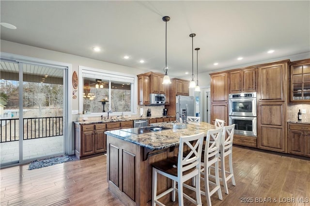 27112 White Horse Cir, Rocky Mount, MO 65072 - kitchen with appliances with stainless steel finishes, brown cabinetry, light wood-style flooring, stone counters, and recessed lighting