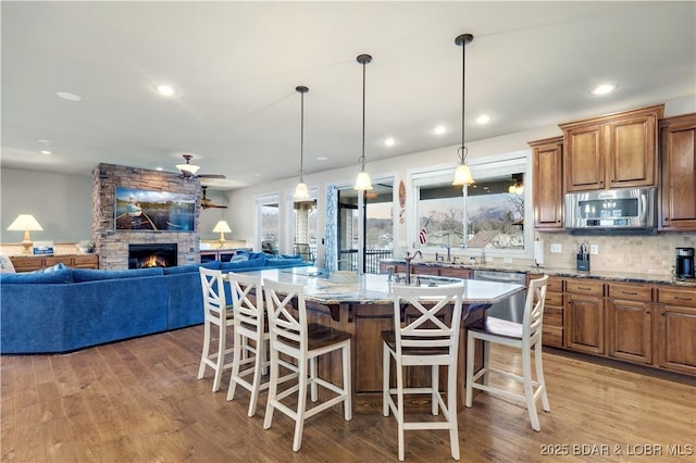 27112 White Horse Cir, Rocky Mount, MO 65072 - kitchen featuring appliances with stainless steel finishes, light wood-style floors, light stone counters, a breakfast bar, and recessed lighting