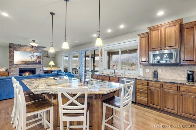 27112 White Horse Cir, Rocky Mount, MO 65072 - kitchen featuring appliances with stainless steel finishes, a sink, light stone countertops, open floor plan, and recessed lighting