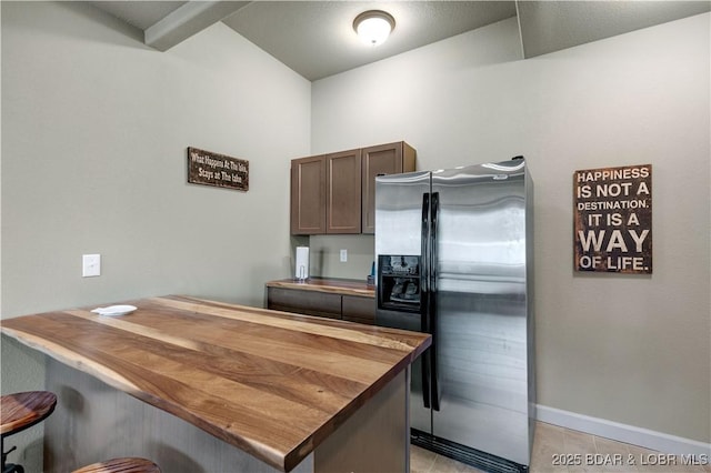 27112 White Horse Cir, Rocky Mount, MO 65072 - kitchen with stainless steel refrigerator with ice dispenser, wood counters, a breakfast bar area, light tile patterned floors, and baseboards