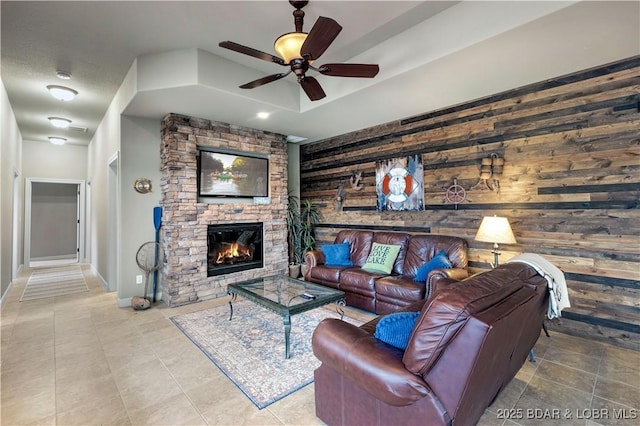 27112 White Horse Cir, Rocky Mount, MO 65072 - living room featuring a ceiling fan, a fireplace, wooden walls, tile patterned floors, and baseboards