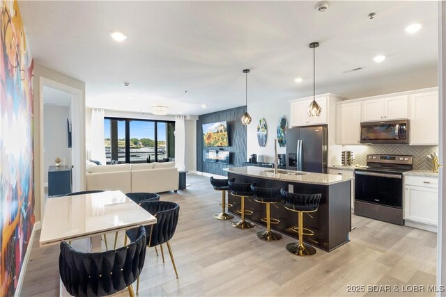 kitchen with appliances with stainless steel finishes, open floor plan, light stone counters, and decorative backsplash