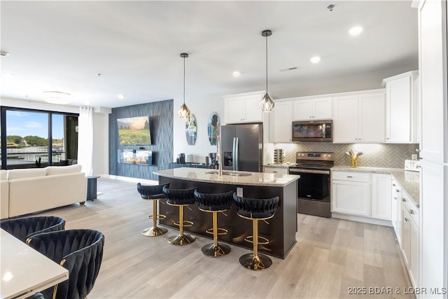 kitchen with light stone counters, stainless steel appliances, a breakfast bar, open floor plan, and decorative backsplash