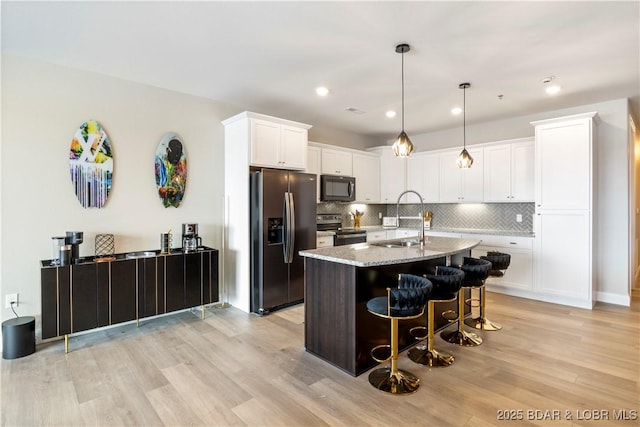 kitchen featuring decorative backsplash, appliances with stainless steel finishes, a kitchen breakfast bar, a kitchen island with sink, and a sink