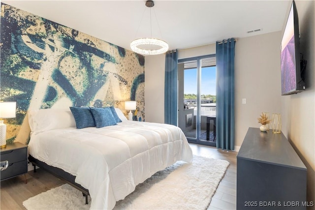 bedroom featuring access to exterior, visible vents, and wood finished floors