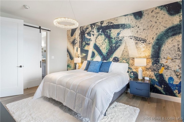 bedroom featuring a barn door, baseboards, and wood finished floors