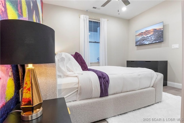 bedroom with ceiling fan, wood finished floors, visible vents, and baseboards