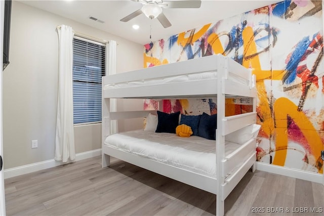 bedroom with a ceiling fan, wood finished floors, visible vents, and baseboards