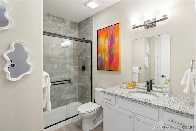 full bathroom with a stall shower, vanity, and toilet