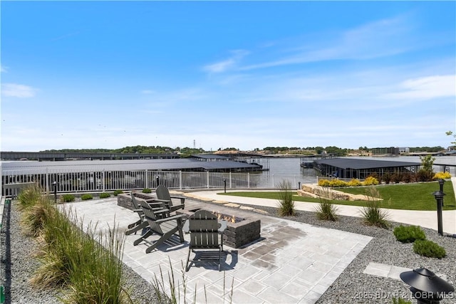 view of patio / terrace with a water view, an outdoor fire pit, fence, and a dock