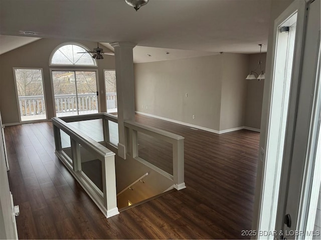 hallway featuring lofted ceiling, a notable chandelier, dark hardwood / wood-style floors, and ornate columns