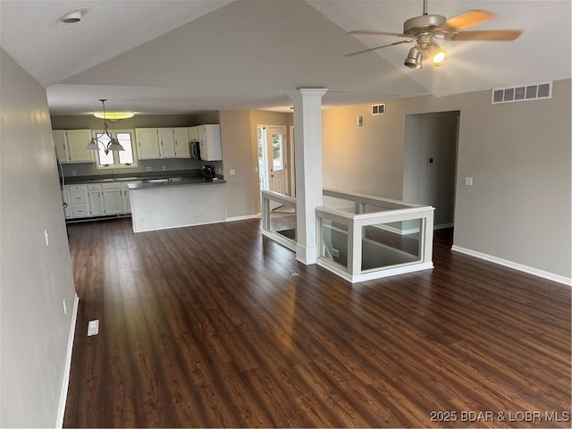 spare room with lofted ceiling, dark hardwood / wood-style flooring, decorative columns, and ceiling fan