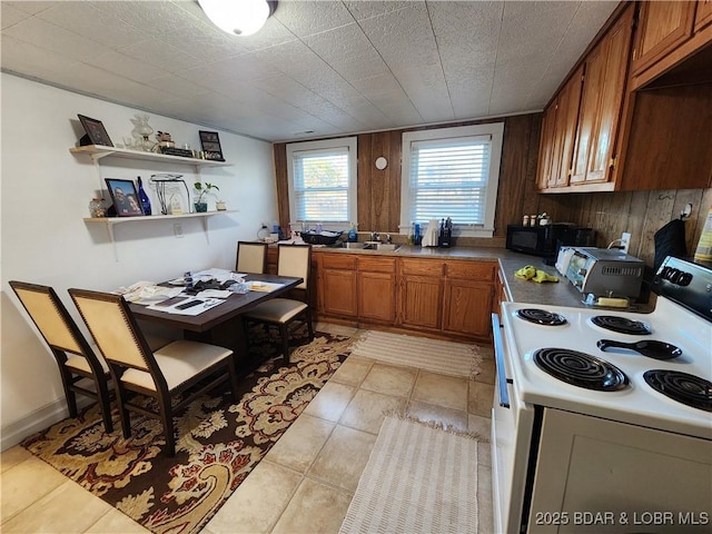 kitchen featuring sink, white electric range, wooden walls, and light tile patterned floors