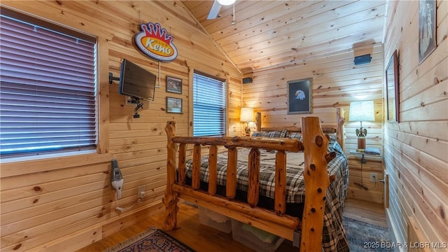 bedroom featuring lofted ceiling, hardwood / wood-style floors, and wooden walls