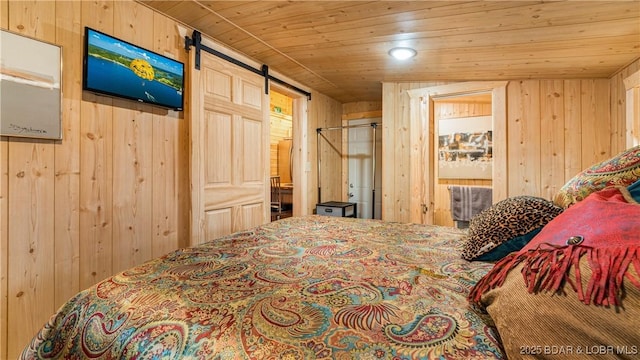 bedroom featuring wood ceiling, a barn door, and wood walls