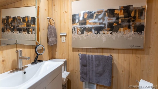 bathroom featuring wooden walls and sink