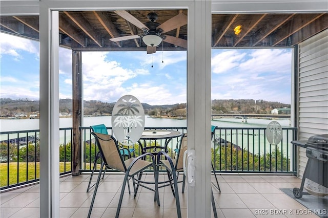 balcony featuring a water view and a ceiling fan