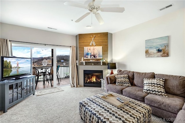 living area featuring ceiling fan, carpet, a fireplace, and visible vents