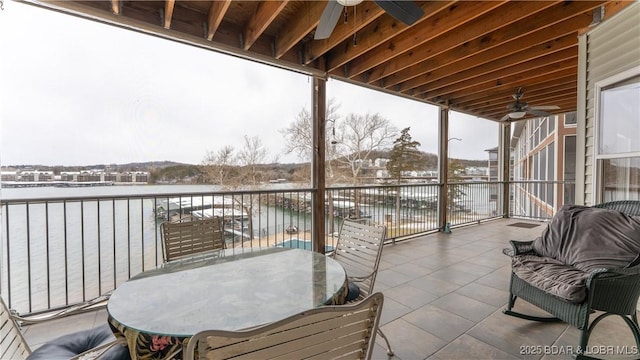 snow covered back of property with a water view and ceiling fan