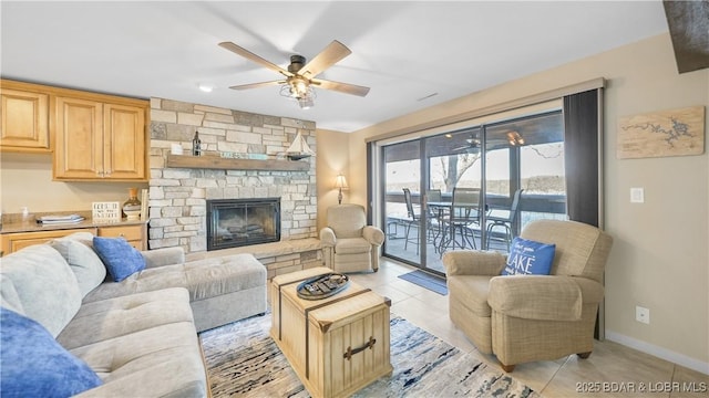 living room with a stone fireplace, light tile patterned floors, and ceiling fan