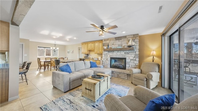 living room with a fireplace, ceiling fan with notable chandelier, and light tile patterned floors