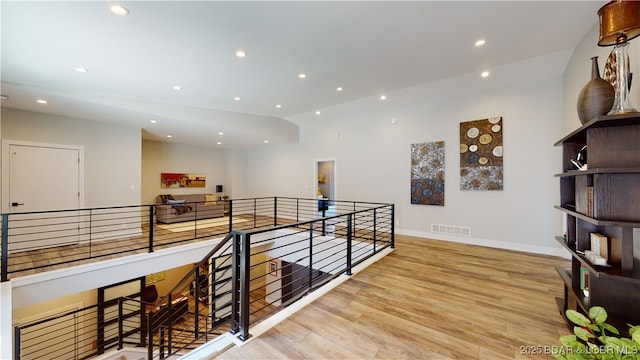 hallway featuring light wood-type flooring and vaulted ceiling