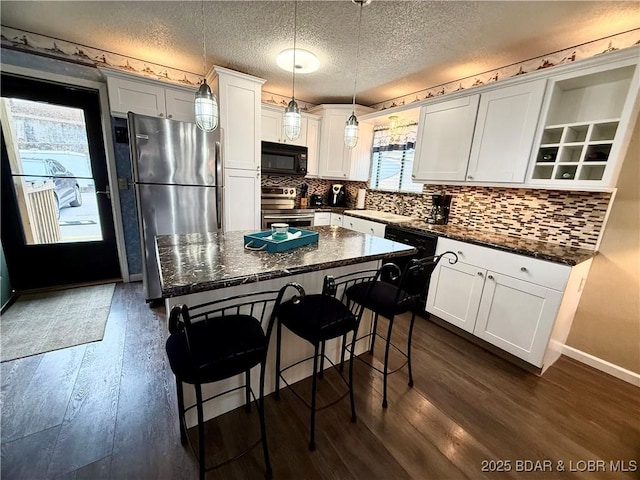 kitchen with black appliances, white cabinetry, decorative light fixtures, and a center island