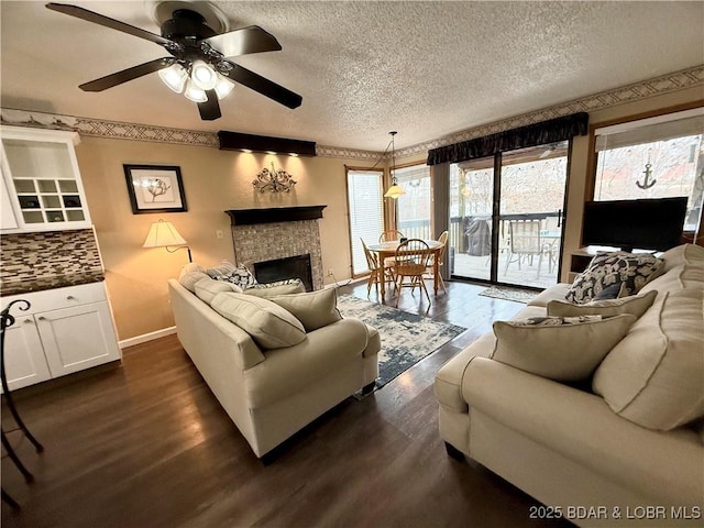 living room featuring a fireplace, ceiling fan, a textured ceiling, and dark hardwood / wood-style flooring