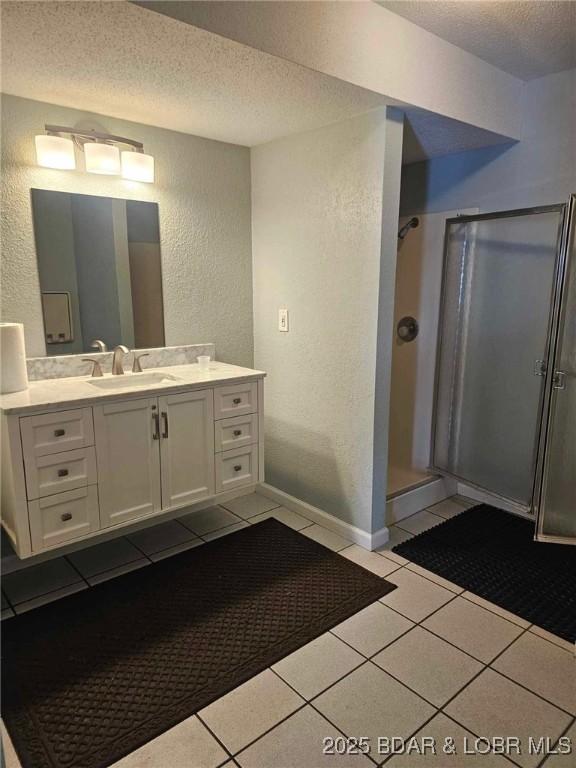 bathroom featuring tile patterned floors, vanity, a textured ceiling, and a shower with door