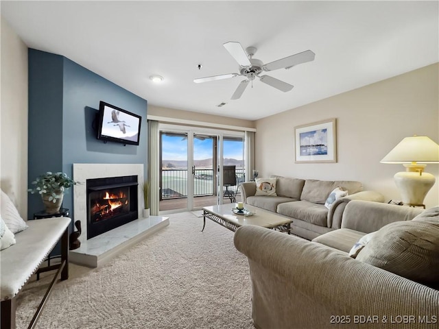 carpeted living room with ceiling fan and a premium fireplace