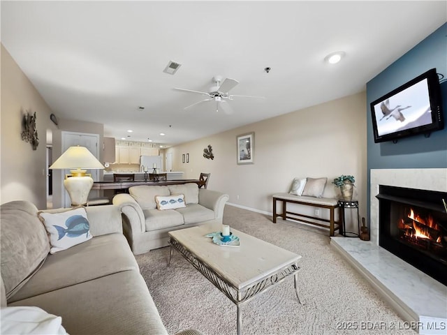 living room featuring ceiling fan, light colored carpet, and a fireplace