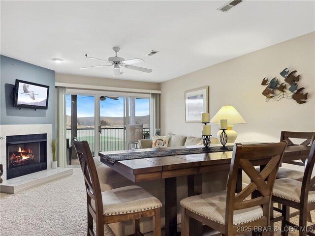 133 Cedar Glen Ct Unit 3D, Camdenton, MO 65020 - carpeted dining room with a warm lit fireplace and ceiling fan