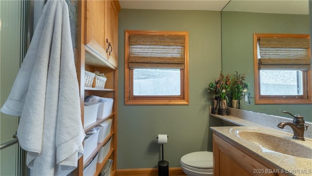 bathroom with toilet, vanity, and a wealth of natural light