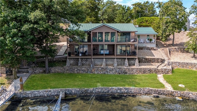 back of house with a yard, a water view, and a balcony