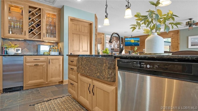 kitchen featuring tasteful backsplash, dark stone counters, stainless steel dishwasher, decorative light fixtures, and fridge