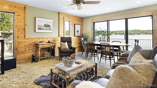 living room featuring a water view, ceiling fan, and wood walls