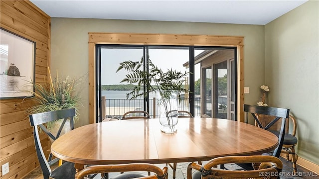 dining space featuring a water view and wood walls