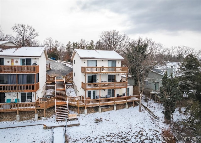 snow covered property with a deck and a balcony