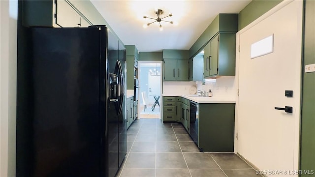 kitchen with sink, green cabinetry, black appliances, and dark tile patterned floors