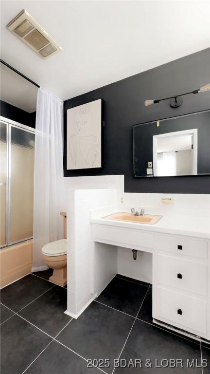 full bathroom featuring tile patterned floors, toilet, sink, and combined bath / shower with glass door