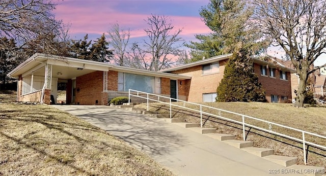 tri-level home featuring an attached carport, brick siding, and driveway