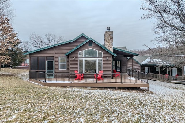 rear view of house featuring a sunroom, a chimney, log veneer siding, and a deck