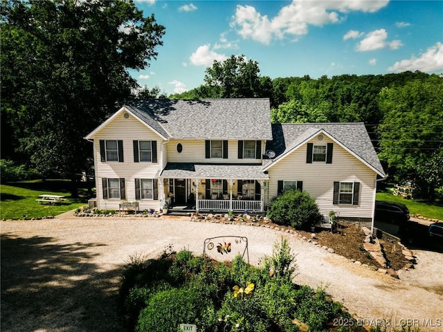 view of front of property featuring roof with shingles, covered porch, and dirt driveway