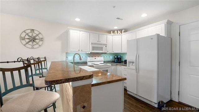 316 Cedar Heights Dr Unit 2C, Camdenton, MO 65020 - kitchen featuring white appliances, a peninsula, white cabinets, decorative backsplash, and dark wood-style floors