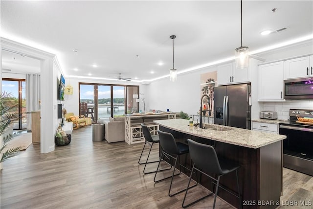 1065 Topsider Ln Unit 408, Osage Beach, MO 65065 - kitchen featuring appliances with stainless steel finishes, a sink, light stone countertops, a kitchen breakfast bar, and white cabinetry