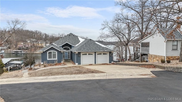 view of front of property with a garage, concrete driveway, roof with shingles, and stairs