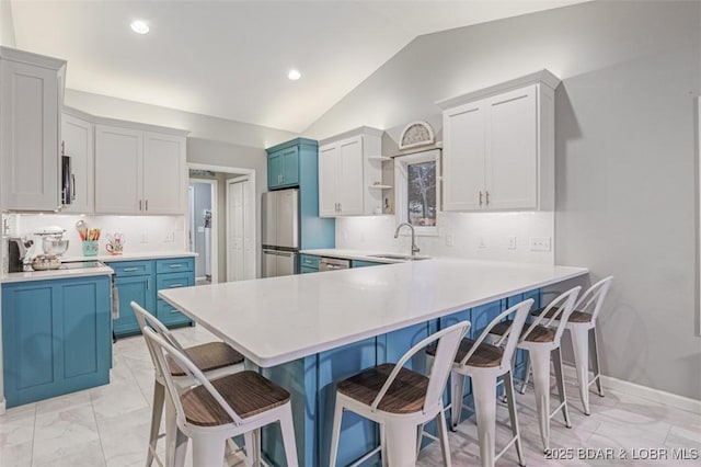 kitchen featuring blue cabinets, appliances with stainless steel finishes, a kitchen breakfast bar, and a sink